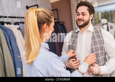Tailor adjusting a waistcoat on a smiling client in a clothing boutique Stock Photo