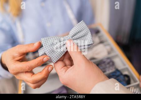 Close-up of hands holding a light blue patterned bow tie in a tailor shop Stock Photo