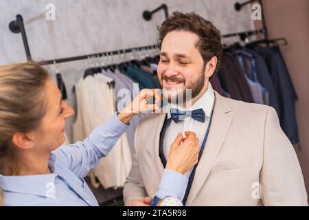 Tailor adjusting a tie for a happy client in a suit boutique Stock Photo