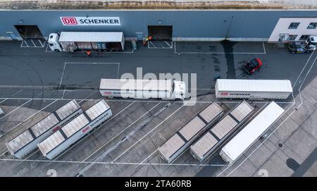Rostock, Germany. 21st Nov, 2023. Trucks of the logistics company DB Schenker are unloaded on the premises of the logistics center in the seaport. (Aerial view with a drone) The logistics subsidiary of Deutsche Bahn operates several logistics centers in Mecklenburg-Vorpommern. Credit: Jens Büttner/dpa/Alamy Live News Stock Photo