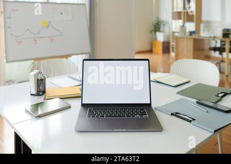 Laptop with empty screen on desk in boardroom Stock Photo