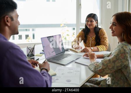Businessman presenting ideas to smiling coworkers in meeting Stock Photo
