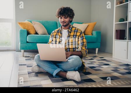 Photo of confident successful engineer administrator working from home sitting on carpet workspace workstation indoors Stock Photo