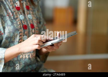 Hands of Indian businesswoman in traditional dress using application on smartphone to check her company performance Stock Photo