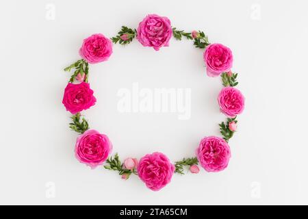 Floral wreath made of pink roses and green branches on a white background. Stock Photo