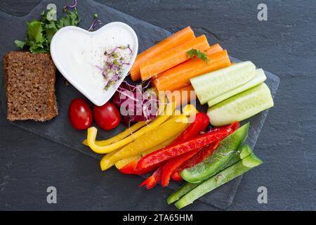 Assorted fresh chopped vegetables with dip on dark background, tasty and healthy snack Stock Photo