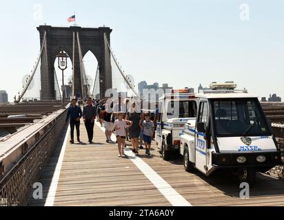 New York, USA - May 25, 2018:Police car and crowd of people on the Brooklyn Bridge with financial district in lower Manhattan at the background. Stock Photo