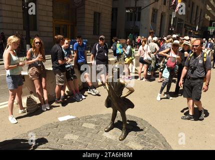 New York, USA - May 2018: People near the 'The Fearless Girl' statue facing the Charging Bull in New York. Stock Photo