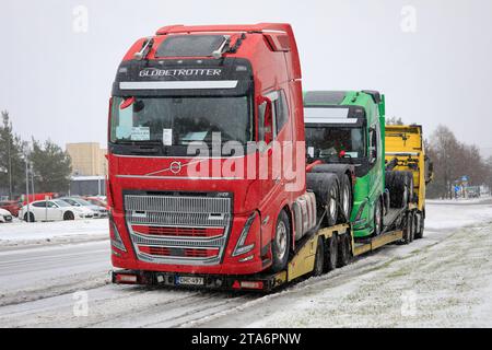 New, red Volvo FH16 truck Globetrotter cab and green Volvo truck loaded on Volvo vehicle carrier lorry in winter. Salo, Finland. November 24, 2023. Stock Photo