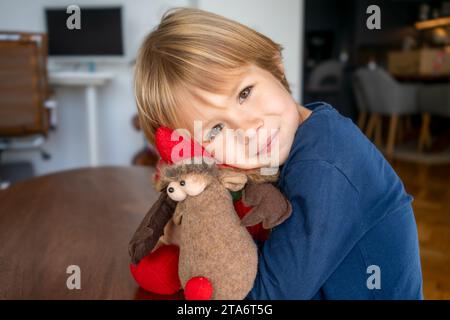 Cute happy toddler boy hugging stuffed christmas toy at home Stock Photo