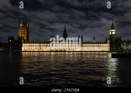 The Palace of Westminster seen lit against a dark sky at night, viewed from the opposite bank of the River Thames, London, UK Stock Photo