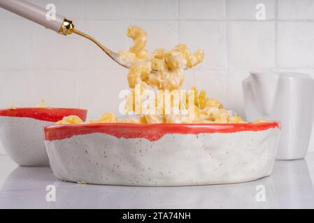 Creamy mac and cheese with ingredients for cooking. Macaroni pasta, bechamel cream sauce, milk, cheese for making mac and cheese on a white marble kit Stock Photo