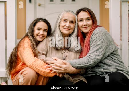 Portrait of smiling multi-generation family sitting on porch Stock Photo