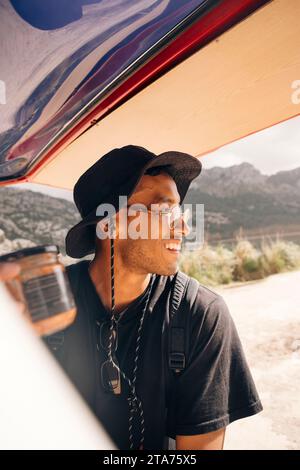 Smiling young man looking away while standing near van Stock Photo