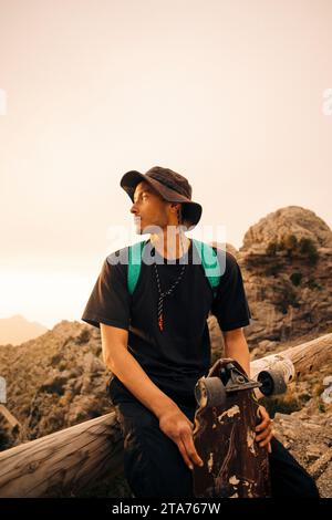 Young man sitting on railing with skateboard Stock Photo