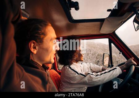 Smiling woman enjoying road trip with male friend sitting in van Stock Photo