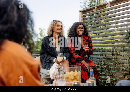 Happy female friends with drinks enjoying during dinner party Stock Photo