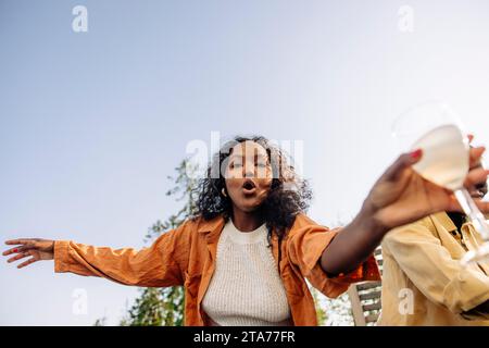 Low angle view of woman dancing with friend during dinner party Stock Photo