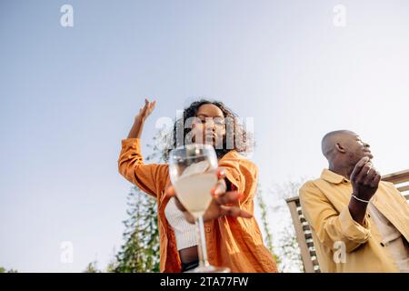 Woman holding drink while dancing with male friend at dinner party Stock Photo