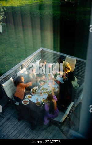 High angle view of male and female friends having food at dining table seen through window Stock Photo