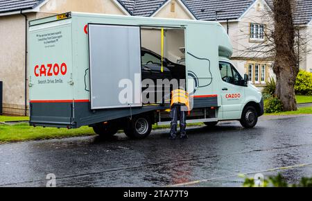 Single black SUV car being delivered to a private home address by a Luton bodied van with side and rear door open and ramp belonging to Cazoo Stock Photo