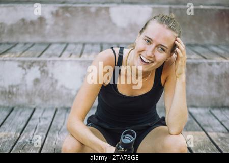 Portrait of happy woman laughing while sitting on steps Stock Photo