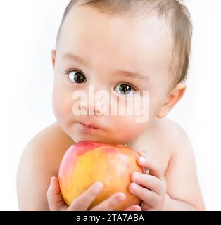 Curious Infant with Bright Eyes Holding a Fresh Apple: A Portrait of Innocence and Exploration Stock Photo