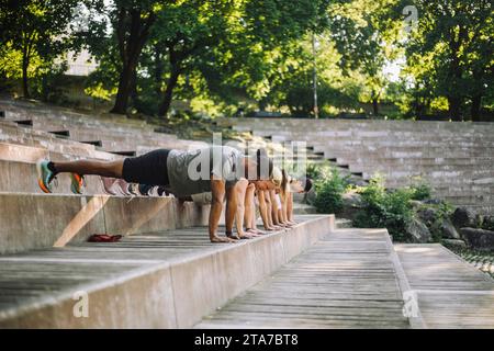 Team of multiracial male and female friends doing push-ups on steps Stock Photo