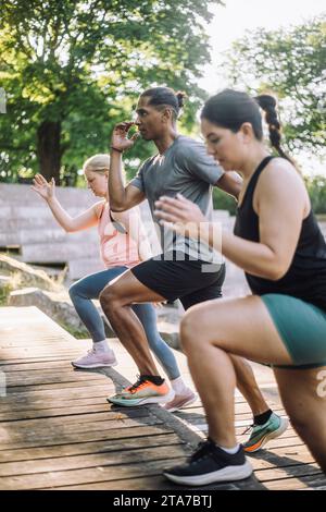 Determined man doing warm up with female friends on steps Stock Photo