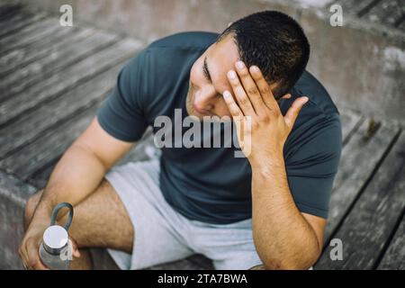 Tired man with head in hand while sitting on steps Stock Photo