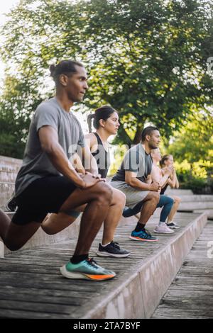 Focused male and female friends practicing lunges on steps Stock Photo