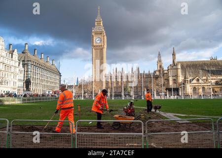 Westminster, London, UK. 28th November, 2023. Workmen were replacing some of the grass turf at Parliament Square today outside the Palace of Westminster in London. A notice from Greater London Authority said 'Due to the heavy rain, the lawn is waterlogged and slippery. The lawn is fenced to provide a period of time for the area to drain and the grass to recover. Please use the paved walkways during this time'. Parliament Square is often busy with people who come to protest outside Parliament. Credit: Maureen McLean/Alamy Live News Stock Photo