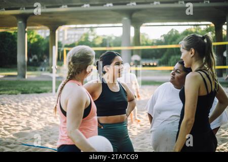 Multiracial female friends talking together while playing volleyball Stock Photo