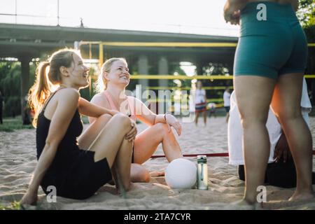 Smiling female friends talking to each other during volleyball match Stock Photo