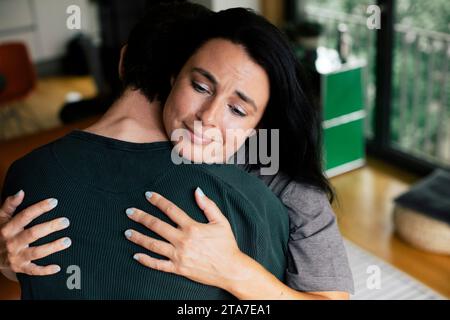 Sad mother embracing son at home Stock Photo