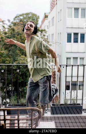 Carefree man listening to music while dancing in balcony Stock Photo