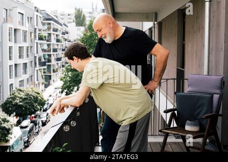 Father talking with son leaning on railing in balcony Stock Photo