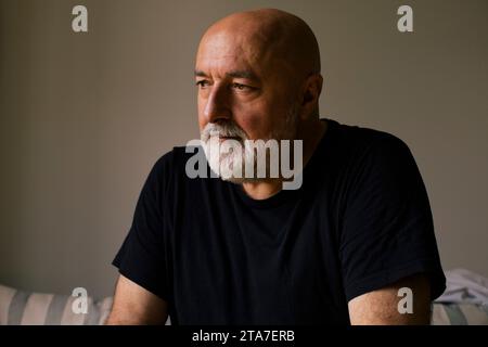Depressed mature man with shaved head at home Stock Photo