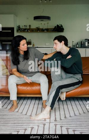 Mother consoling son while sitting on sofa at home Stock Photo