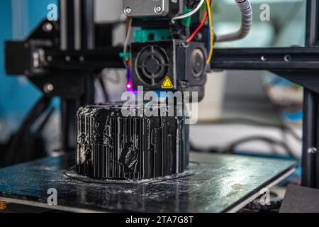 A 3D printer prints a black model. Technology at home Stock Photo