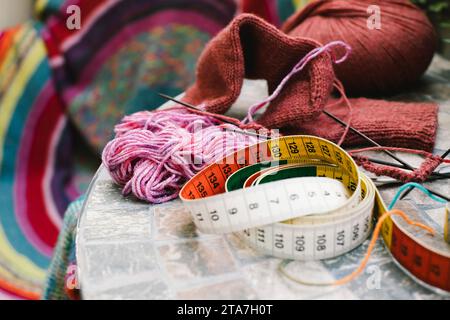 Tape measure with wool and knitting needles on table Stock Photo