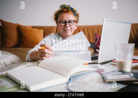 Happy senior woman holding tickets while planning trip Stock Photo