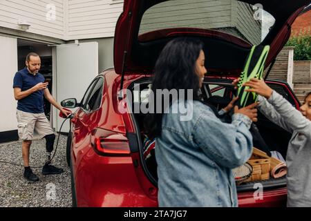 Man with disability using smart phone while charging electric car Stock Photo