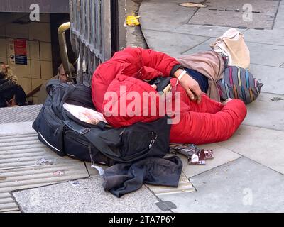 London, UK. 28th November, 2023. A homeless man sadly sleeps on the pavement outside an entrance to Bank Tube Station in the City of London on a cold day. Crisis At Christmas are continuing their fund raising campaign asking people to donate money to help take homeless people off the streets over Christmas and provide them with hot food. Credit: Maureen McLean/Alamy Live News Stock Photo