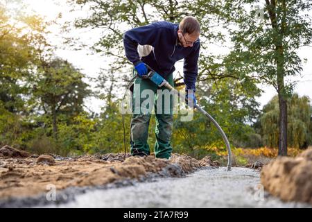 Construction worker using a concrete vibrator to compact the foundation at a building site Stock Photo