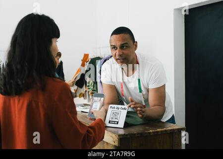 Tailor pointing at bar code scanner while talking to customer in store Stock Photo