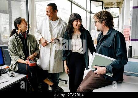 Happy male and female entrepreneurs having fun while talking with each other at repair shop Stock Photo