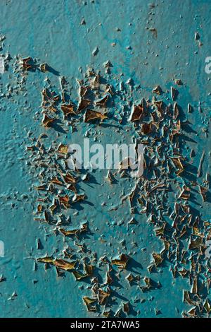 Blue peeling paint on the wall. Old concrete wall with cracked flaking paint. Weathered rough painted surface with patterns of cracks and peeling. Hig Stock Photo