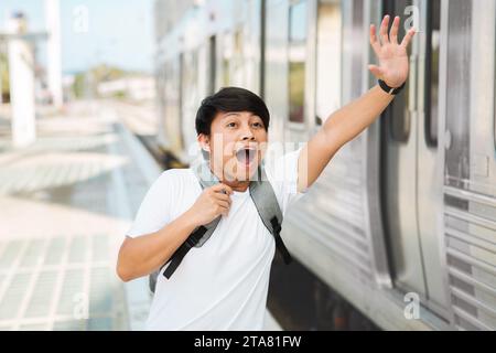 Young asian man with backpack running to catch the train Stock Photo