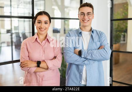 Happy confident young arab woman and european guy manager in casual with crossed arms on chest Stock Photo
